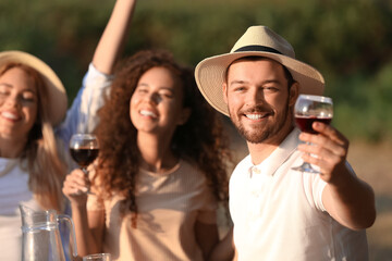 Young man drinking with friends at barbecue party on summer day