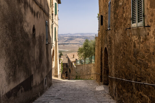 An ancient and narrow sloping alley provides a glimpse on the surrounding Tuscanian landscape