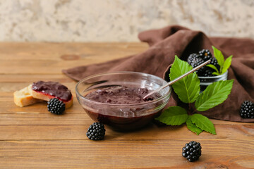 Fototapeta na wymiar Composition with bowl of tasty blackberry jam on wooden table