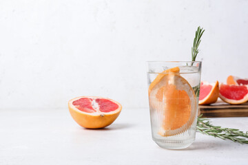 Glass of cold gin tonic and grapefruit slices on light background
