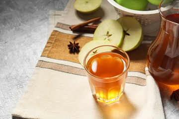 Glass and jug of apple juice on light background