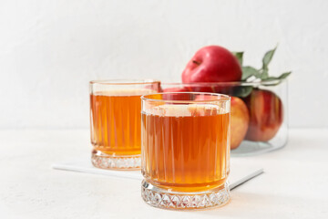 Glasses of apple juice on light background