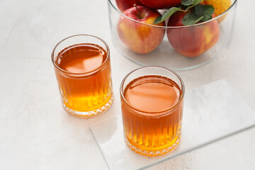 Glasses of apple juice on light background