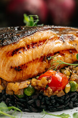 Closeup on gourmet salmon fillet with creamy basil sauce and black rice