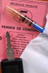 Clé de voiture posée sur un permis de conduire français à côté d'un ethylotest