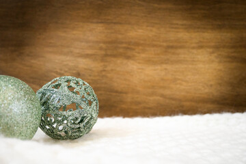 green christmas baubles on white blanket with copy space on wooden wall
