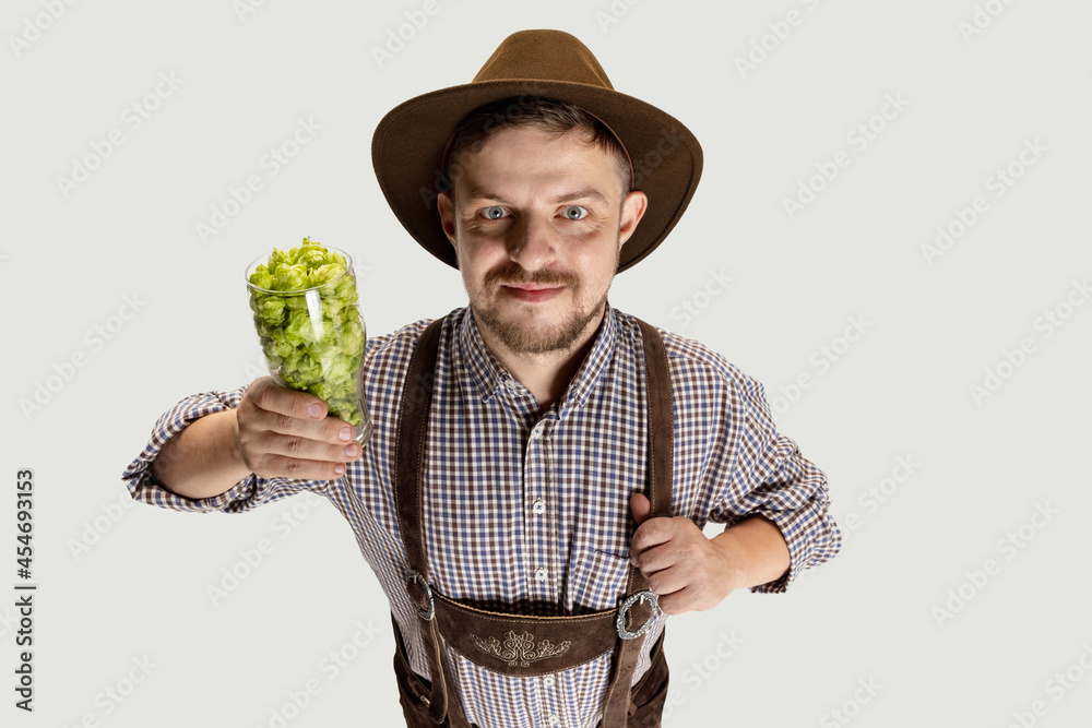 Wall mural Happy smiling man dressed in traditional Bavarian costume holding beer glasses filled with wild hot and barley. Celebration, oktoberfest, festival concept.