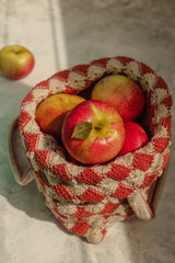 Apples in a bag knitted with an openwork pattern on a light background in hard sunlight.