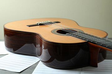 Classical guitar and music sheets on gray textured table