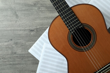 Classical guitar and music sheets on gray textured table