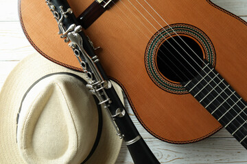 Classical guitar, clarinet and hat on white wooden table