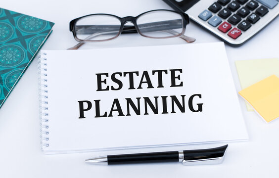 Estate Planning text on notepad on office desk next to glasses, calculator and pen