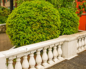A stone staircase with a railing with balustrades descends into the garden with a well-groomed...