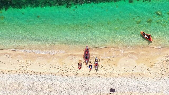 aerial Top view of a couple laying on the beach after summer sport.Blue sea waves and white sand. Aerial view of two unrecognisable people on the seaside with their canoes, sandy, tropical beach.