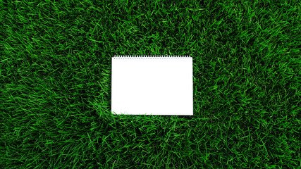 Mock-up empty white paper on green grass background. Сard on nature for message flat lay with copy space for text or products presentation. Nature concept, business and lifestyle environment. Top view