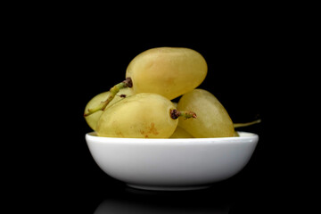 Several berries of ripe sweet grapes with white ceramic dishes, close-up, isolated on black.