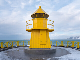 Fototapeta na wymiar Yellow lighthouse on seashore on winter day