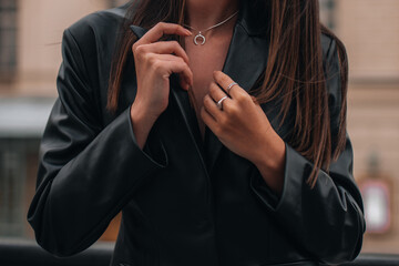 Female hands in a black stylish leather jacket and silver accessories on a female body. Jewelry and women's fashion
