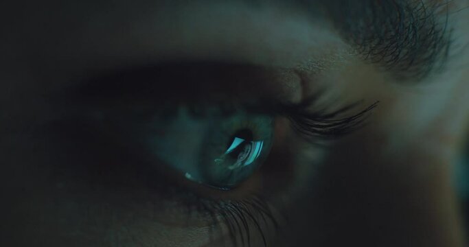 macro eye watching video on tablet screen at night 