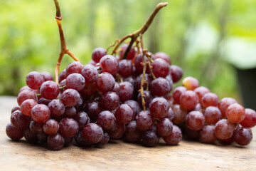 small purple grapes piled on a wooden table