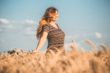 romantic young woman enjoying nature, raising hands on background of cloudy sky in wheat field, girl breathe breathes deeply, freedom and relaxation concept
