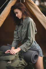 Camping with tents. Sexy young girl travels with a backpack. The girl on the background of the tent.