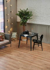 Carpet detail in the room, kitchen table, black chair and grey sofa, lamp, plant and bookshelf background.