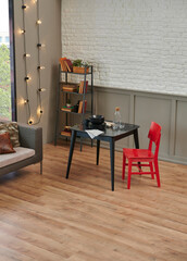 Carpet detail in the room, kitchen table, red chair and grey sofa, lamp, plant and bookshelf background.