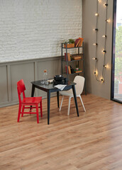 Carpet detail in the room, kitchen table, red chair and grey sofa, lamp, plant and bookshelf background.