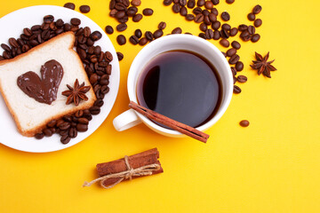 White cup of coffee, heart-shaped toast with nutella chocolate and coffee beans on a yellow background. Flat lay style, top view