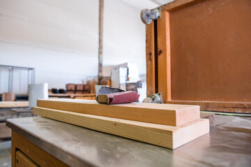 several ecological wood boards, with sandpaper on top in a carpentry workshop