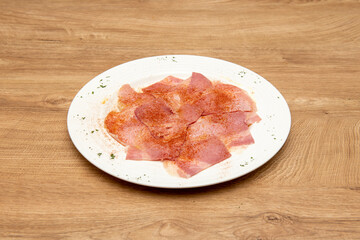Galician cooked lacon slices with olive oil, paprika de la vera and sea salt on wooden table