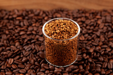 Instant, freeze-dried or granulated coffee in glass on background of roasted coffee beans. Used to make a cold Dalgon coffee drink. Side view, closeup, selective focus