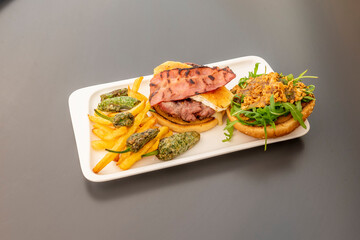 Gourmet beef burger with goat cheese, fried bacon with crispy onion with arugula and fried potatoes with padron peppers