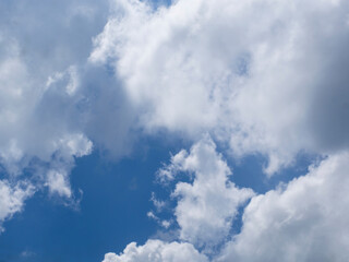 Fototapeta premium Abstract textured background of white clouds and blue sky. Large light blue cumulus clouds close-up, beautiful background of a cloudy sky, view of a sunny cloudy sky, landscape with clouds, postcard