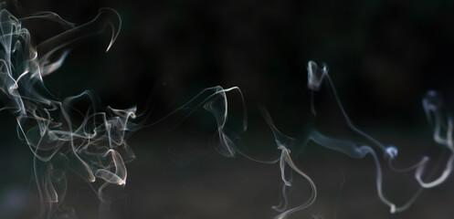 Smoke from incense sticks and burning incense on a black background. Beautiful smoke for design with copy space. Banner. Horizontal format. Copyspace