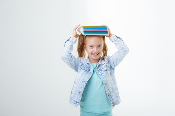 a little girl with a book on her head on a white background is isolated