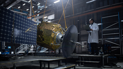 Industrial Engineer Working on Artificial Satellite Construction. Aerospace Agency: Scientist Using Laptop Computer to Develop Spacecraft for Space Exploration and Data Communication.
