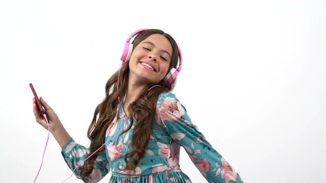 cheerful dancing child hold cell phone listening music in headphones with peace gesture, music lover