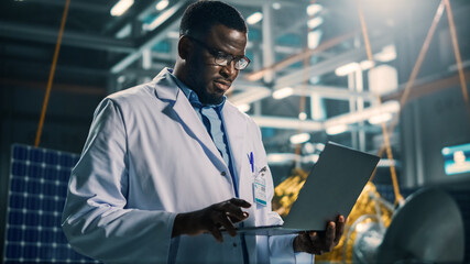 Industrial Engineer Working on Artificial Satellite Construction. Aerospace Agency: African American Scientist Using Laptop Computer to Develop Spacecraft for Space Exploration and Data Communication.