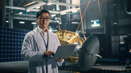 Portrait of Serious Asian Engineer Working on Artificial Satellite Construction. Aerospace Agency:...