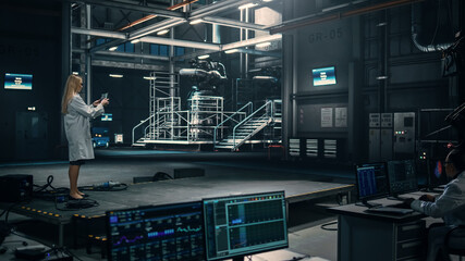 Female Engineer Uses Tablet Computer while Working in an Industial Facility at a Factory. Scientist uses Augmented Reality Software. Empty Space Left for Mock Up Template for VFX.