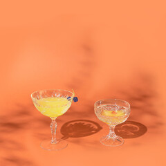 One glass have two chokeberries on top of it. Two striking crystal glasses with magic cocktails against orange background. Moody chill out vibe around.