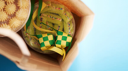 hand holding paper bag with cookies and ribbon ketupat as gift for friend and relative