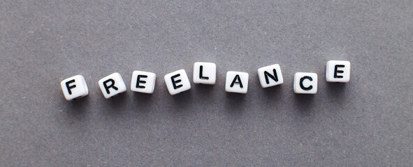 word freelance made from plastic cubes of beads on gray background. banner