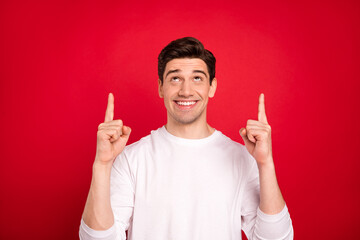 Photo of curious brunet young guy point up wear white shirt isolated on red color background