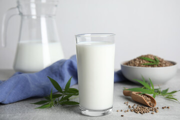 Hemp milk, seeds and fresh leaves on light grey table