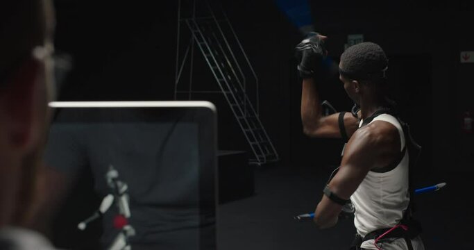 mocap man wearing motion capture suit in studio using escrima sticks fighting martial arts actor wearing mo-cap suit for 3d character animation for virtual reality gaming industry