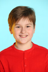 Close-up portrait: trendy, cheerful teenage boy in a red sweater. He smiles broadly and looks eye to eye.