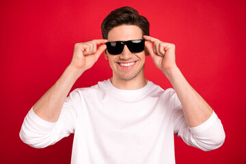 Photo of cool brunet young guy hands eyewear wear white shirt isolated on red color background